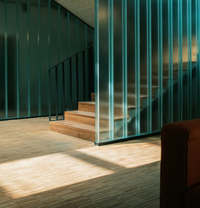 Ein Wohnzimmer mit hellblauer Glastrennwand und Treppe